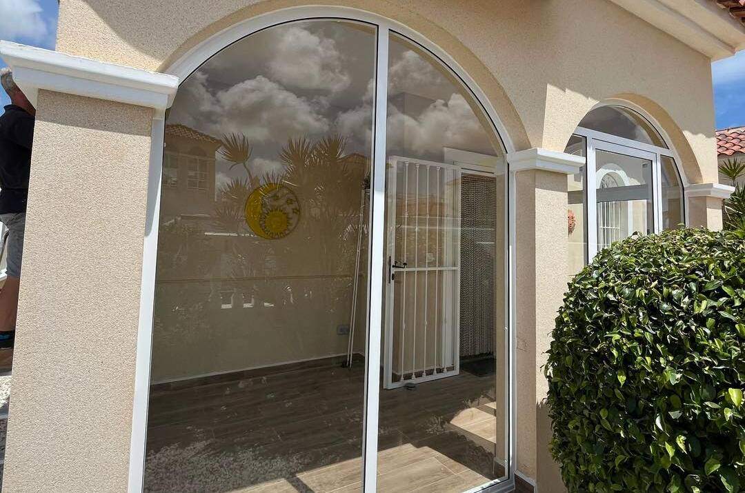 Freshly installed large porch window with rounded top.