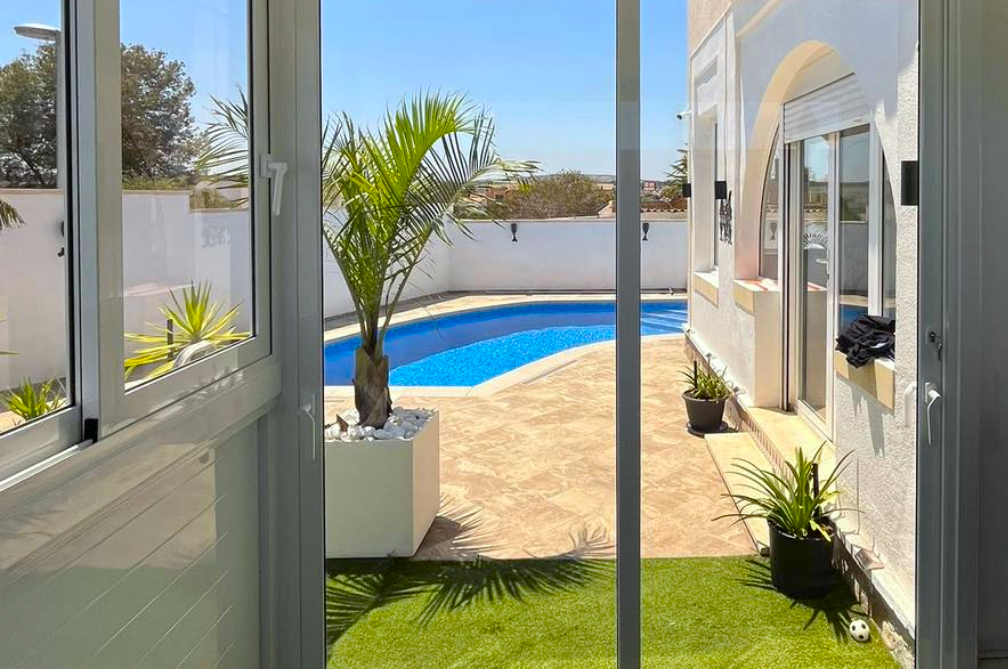 Floor to ceiling sliding door windows overlooking curved pool in rear garden of property.